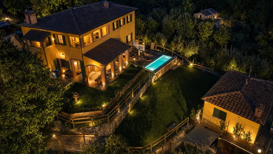 The villa and its pool aglow from above after dark