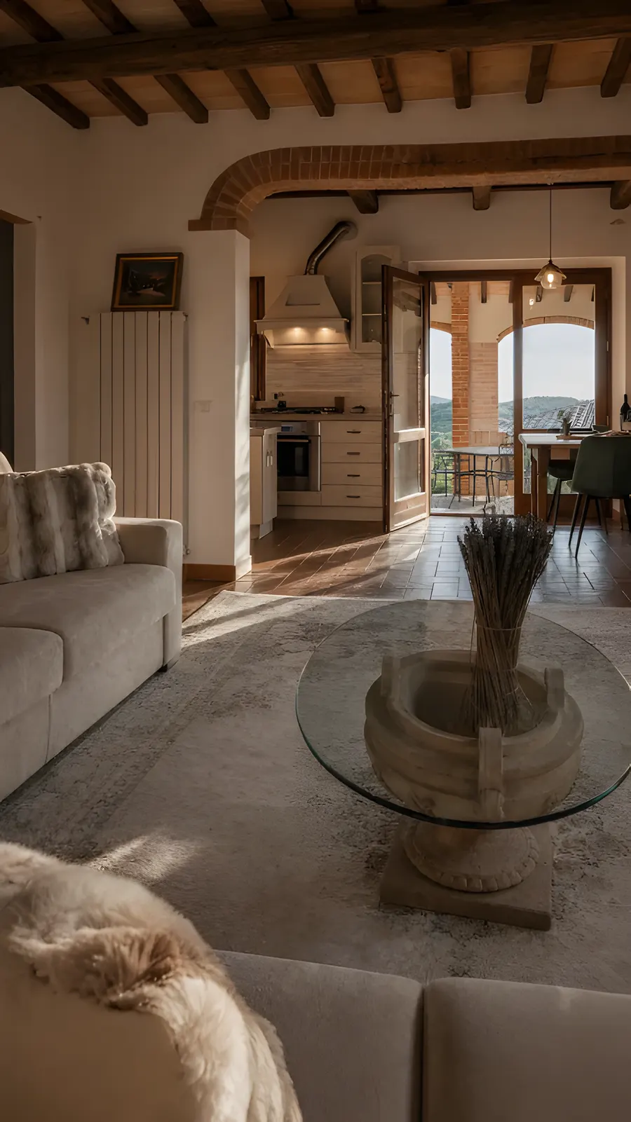 The villa's living room with a stone well-base glass table and dried lavender, the kitchen and valley view beyond