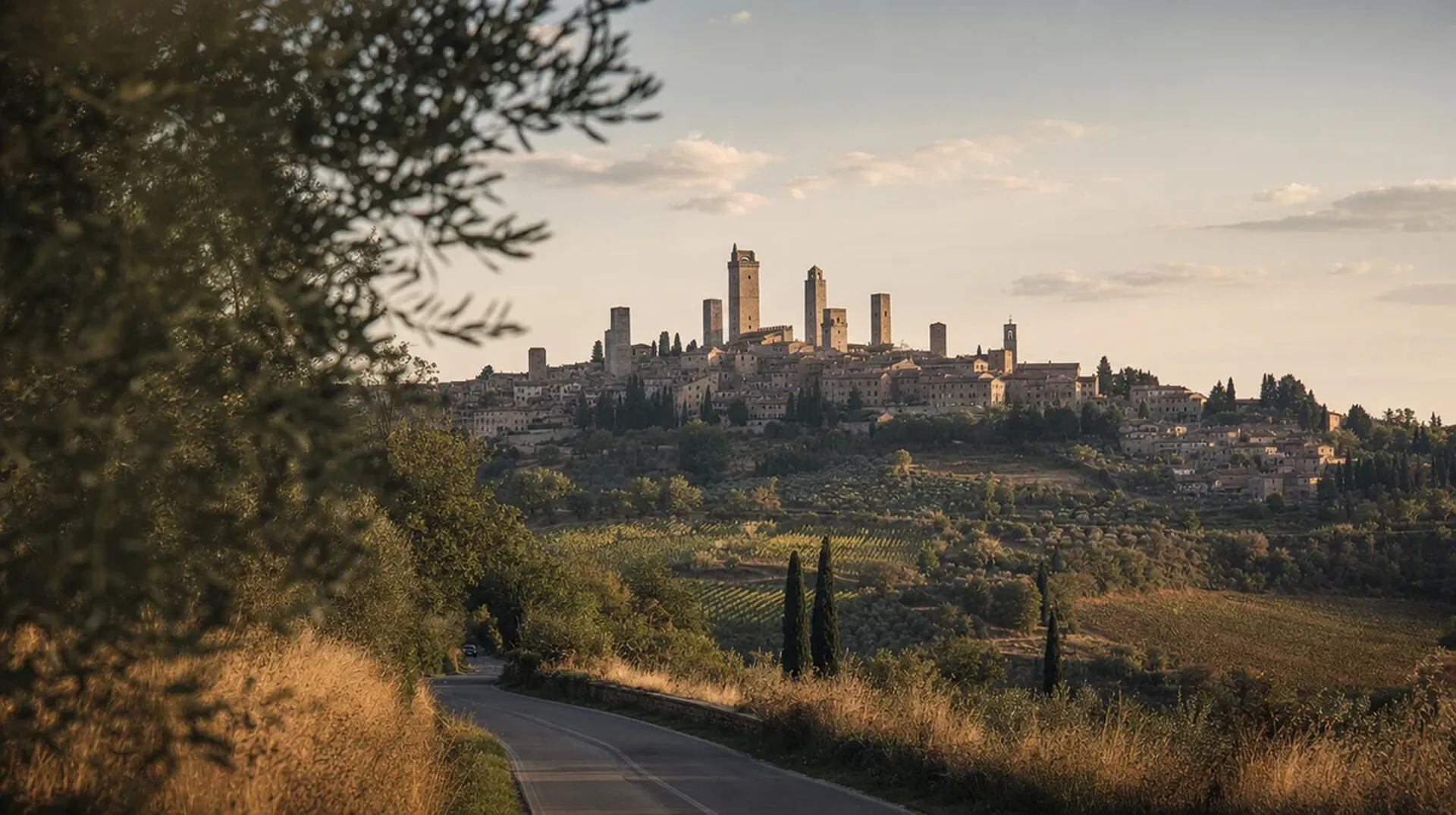 The medieval towers of San Gimignano rising above terracotta rooftops against the Tuscan hills at golden hour